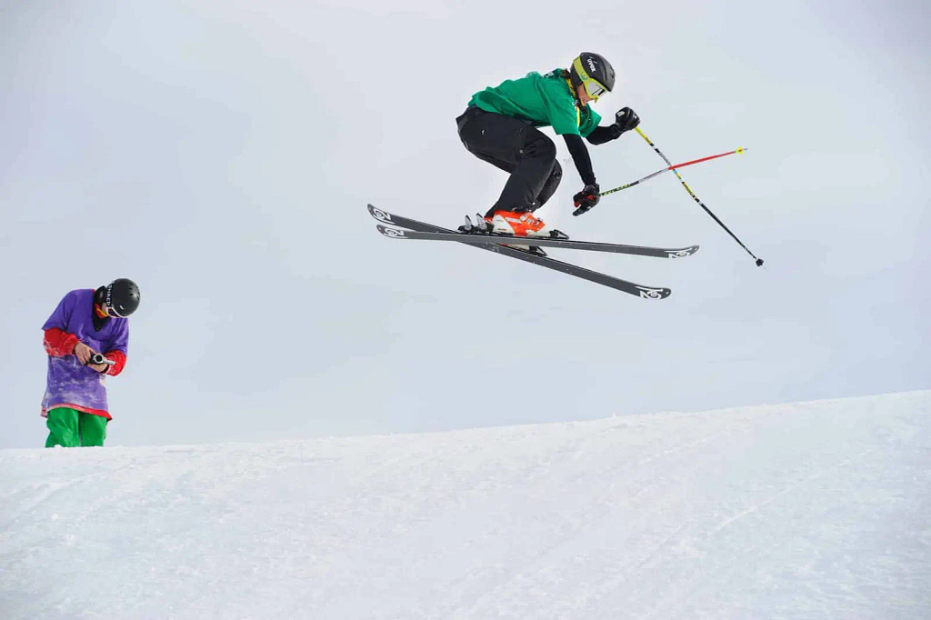 skier in mid air performing tricks, emphasis on knee strength for landing