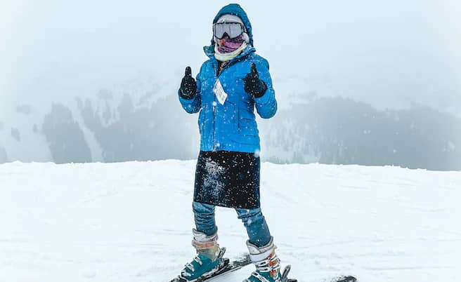 woman in full skiing gear holding thumbs up