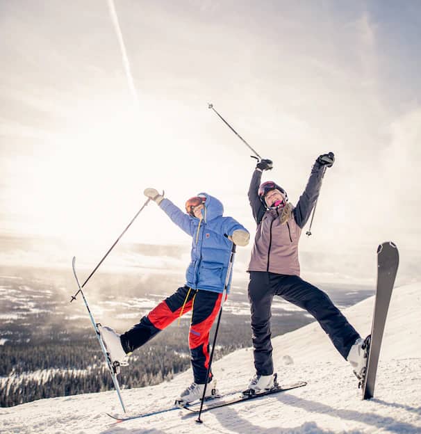 2 persons posing for a photo with skis and ski poles held high